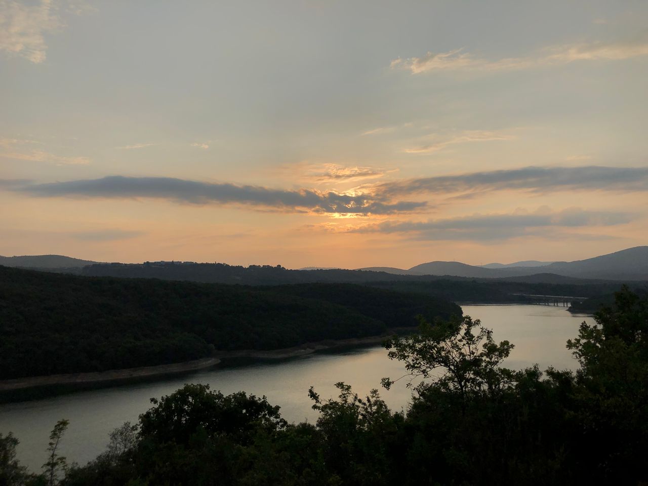 services-img Beautiful sunset over a tranquil river surrounded by lush forests and hills.