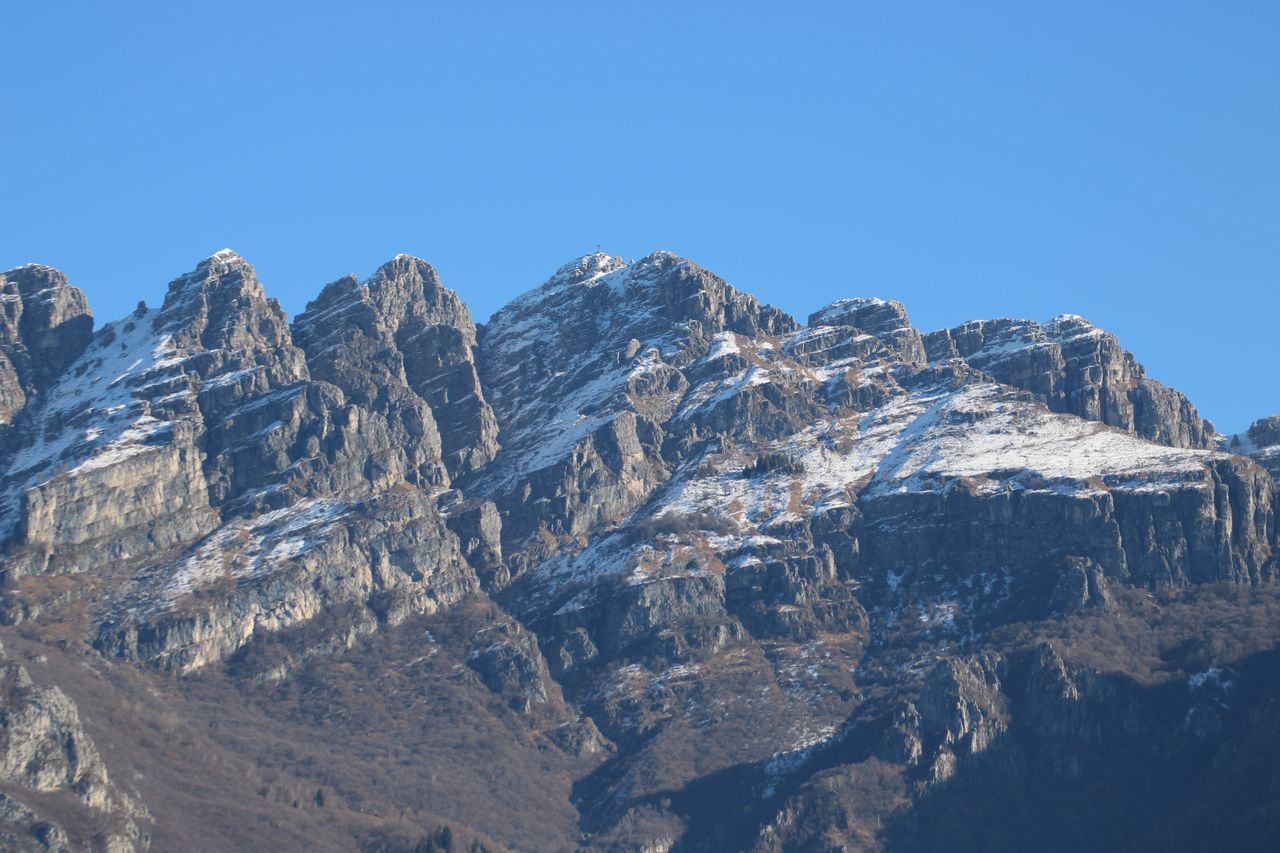 services-01 Breathtaking view of snow-covered mountain peaks in Lombardy, Italy under a clear blue sky.