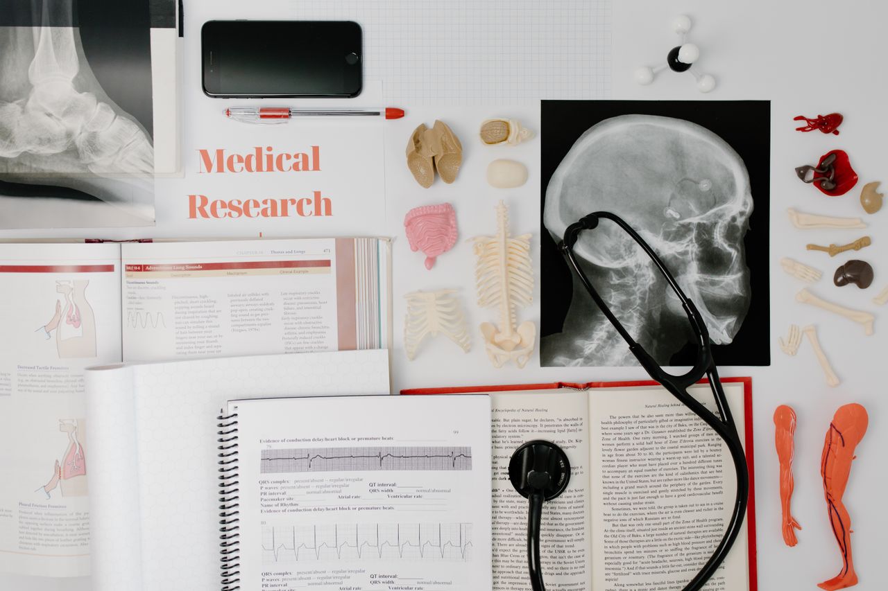 home-img Overhead view of medical research equipment and study materials including books, x-rays, and stethoscope.